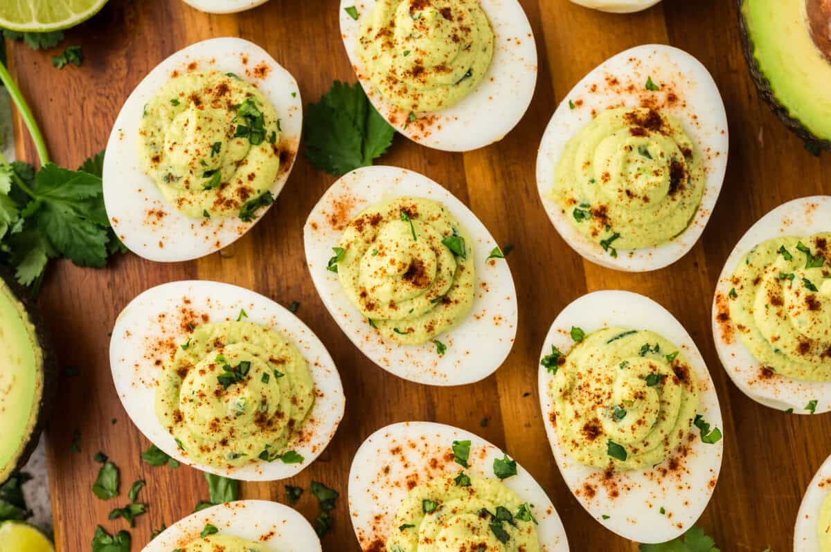Overhead view of avocado deviled egg recipe on wooden board.