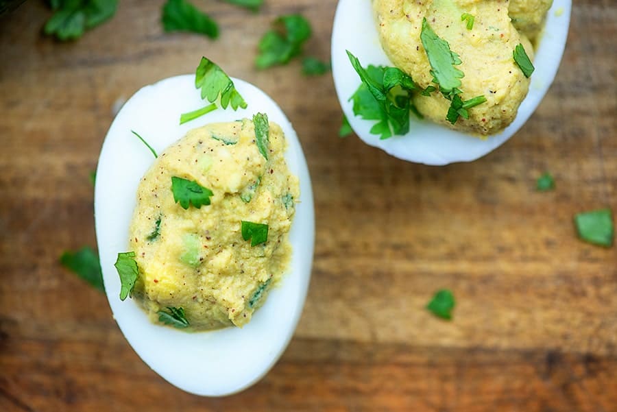 Overblik over avocado-udskyllede æg på et træskærebræt.