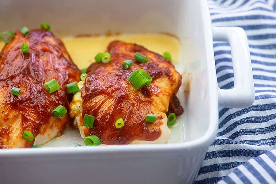 baking dish with raw chicken topped with bbq sauce and chives