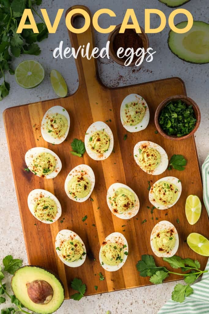 Avocado deviled eggs on wooden cutting board.