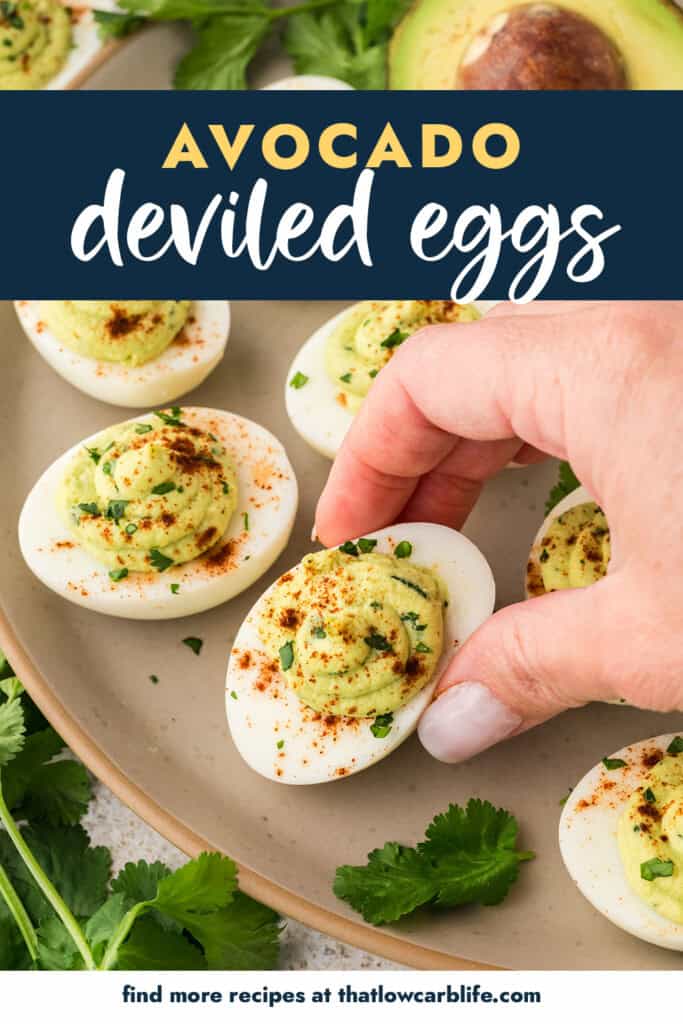 Hand holding a deviled egg made with avocado instead of mayo.