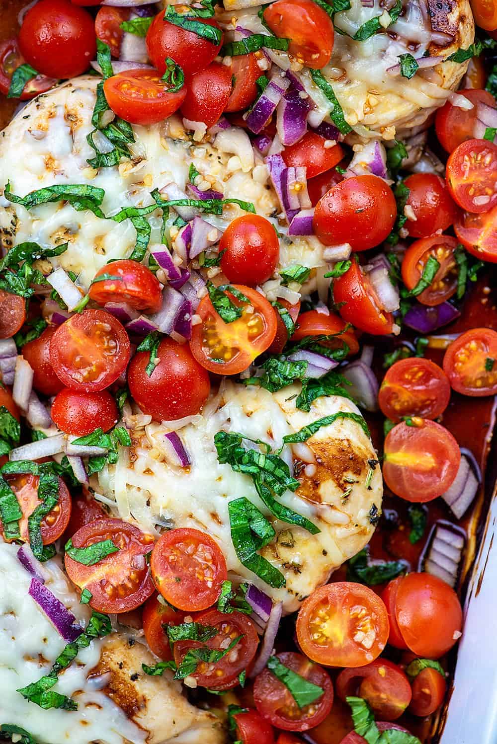 A close up of bruschetta chicken topped with grape tomatoes.