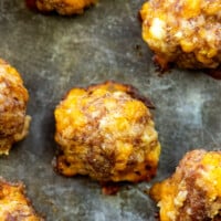 A close up of sausage meatballs on a baking sheet.