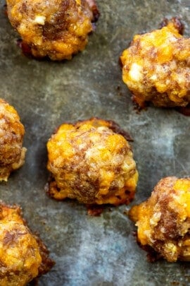 A close up of sausage meatballs on a baking sheet.