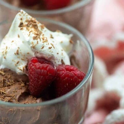 keto chocolate mousse recipe in glass dish with whipped cream and raspberries