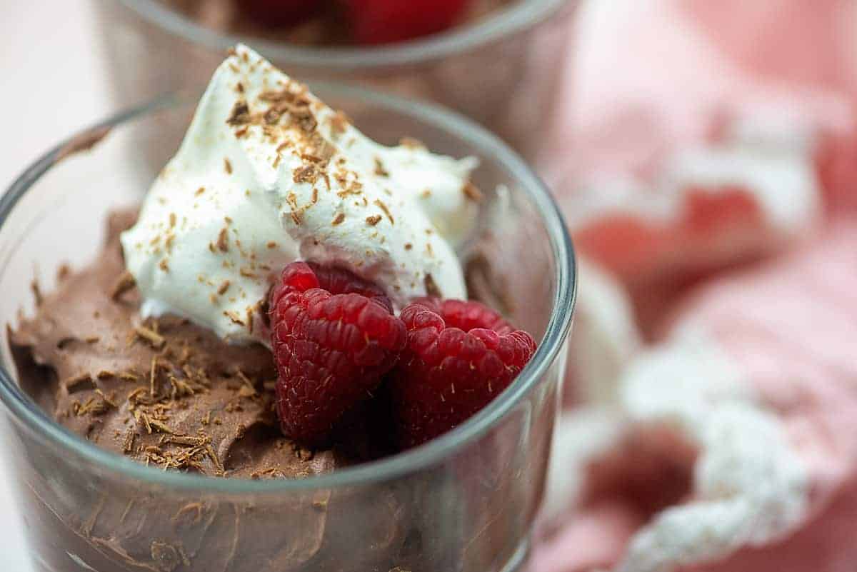 keto chocolate mousse recipe in glass dish with whipped cream and raspberries