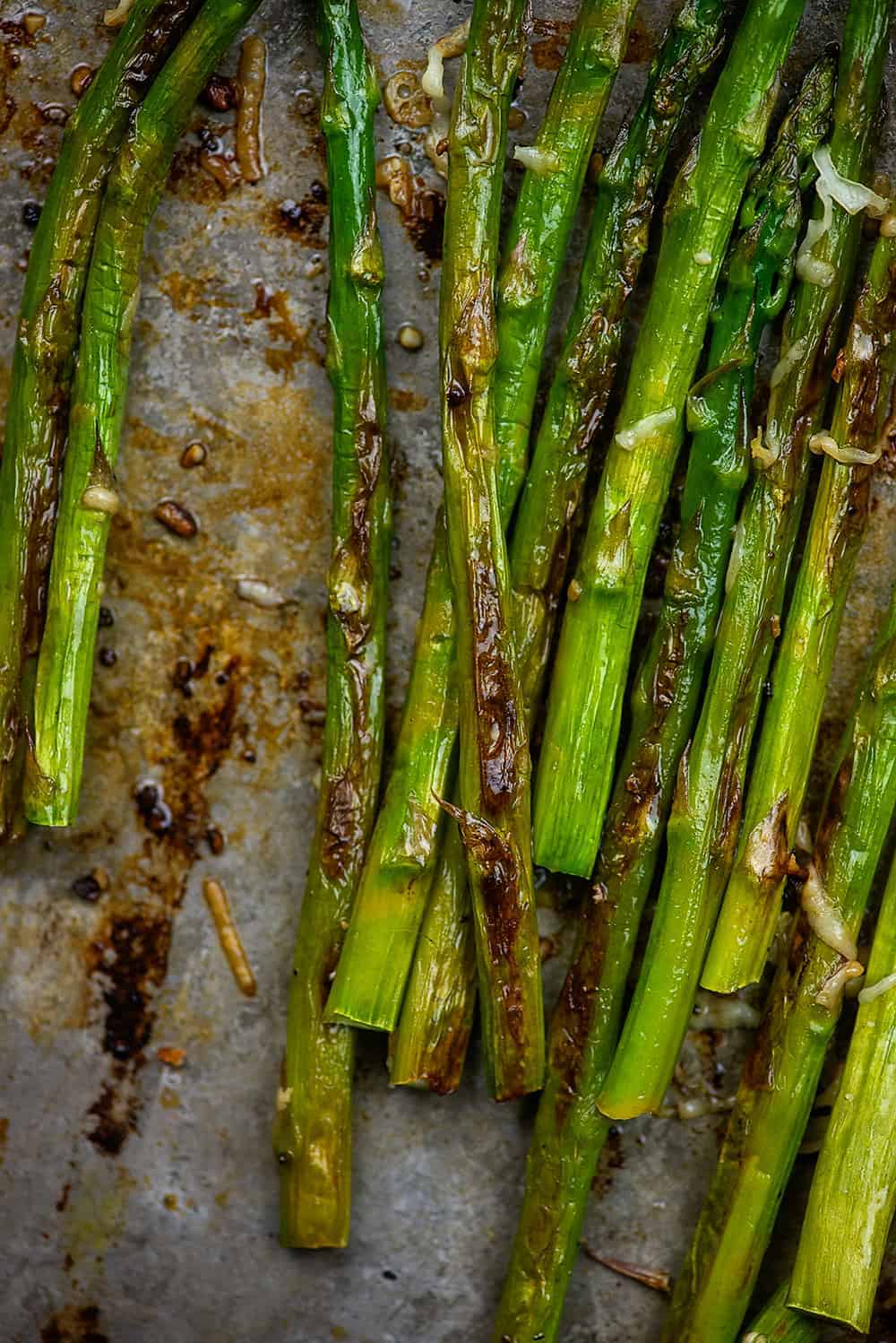 browned asparagus on baking sheet with garlic and parmesan