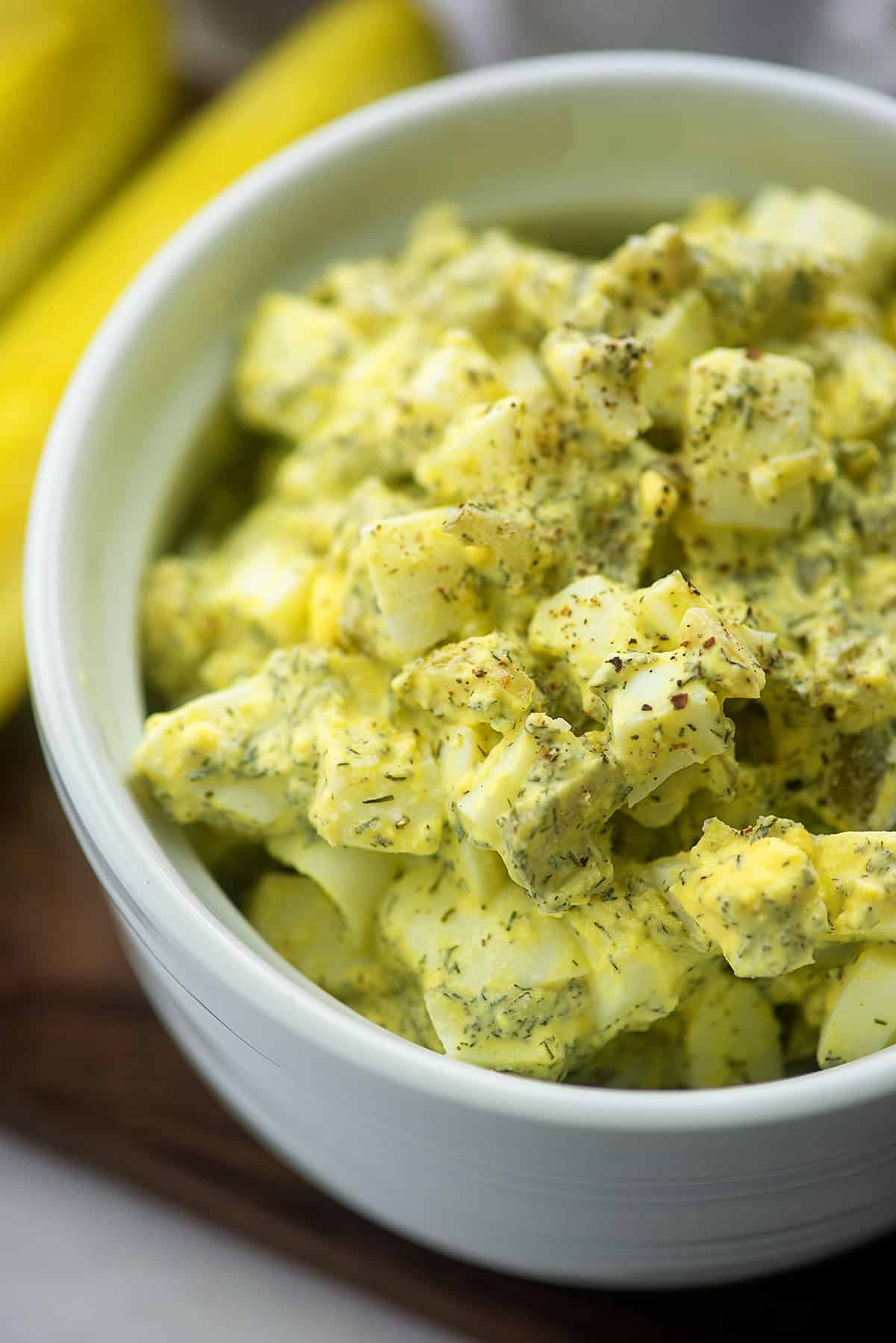 egg salad recipe with dill and pickles in white bowl