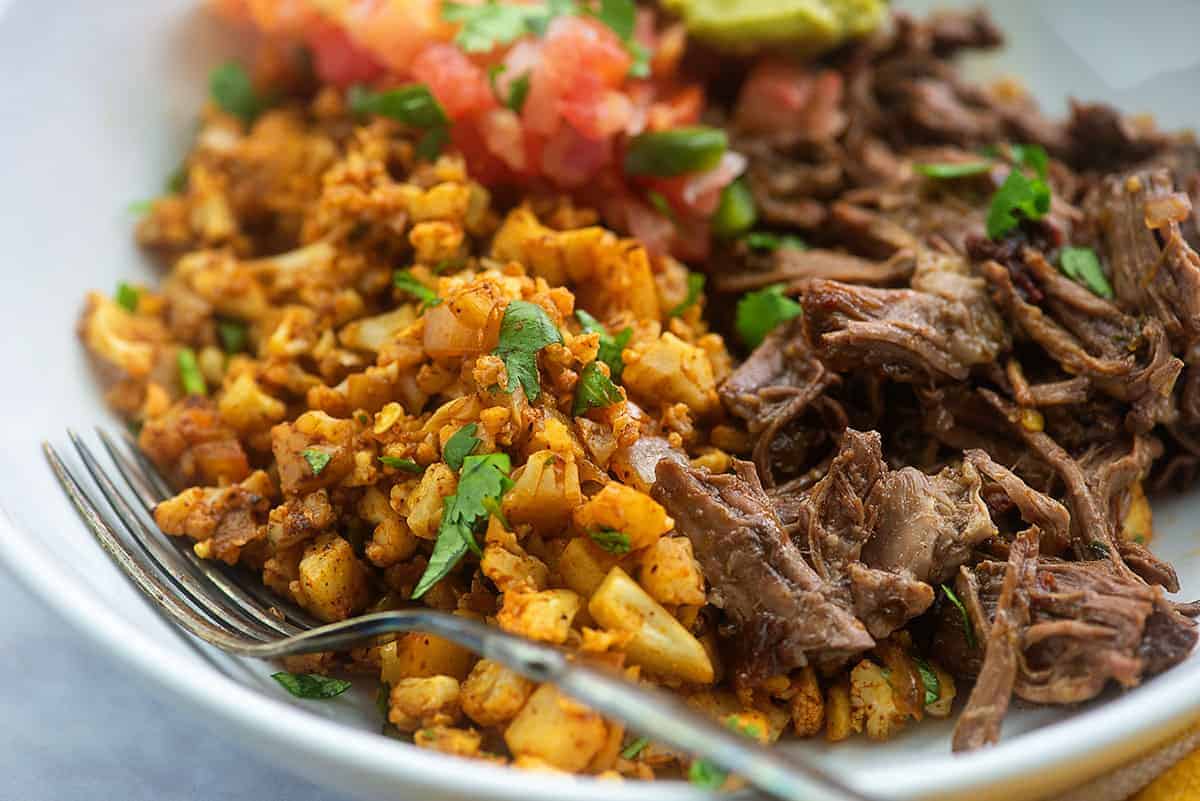 mexican cauliflower rice with barbacoa in white bowl