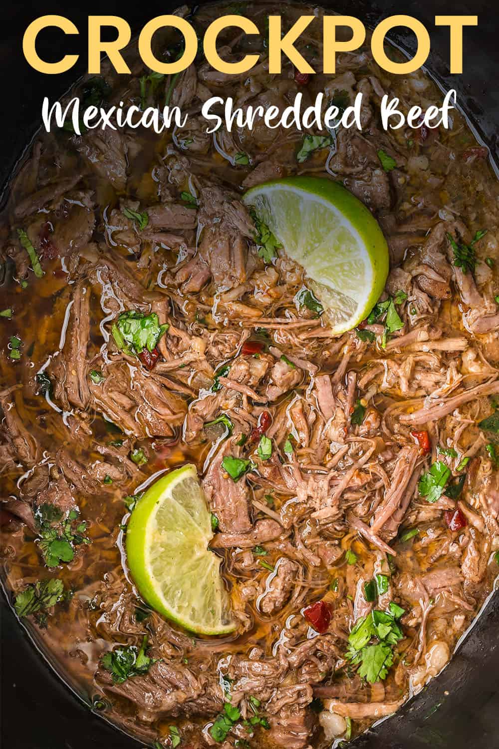 Crockpot Mexican shredded beef topped with lime wedges and cilantro.