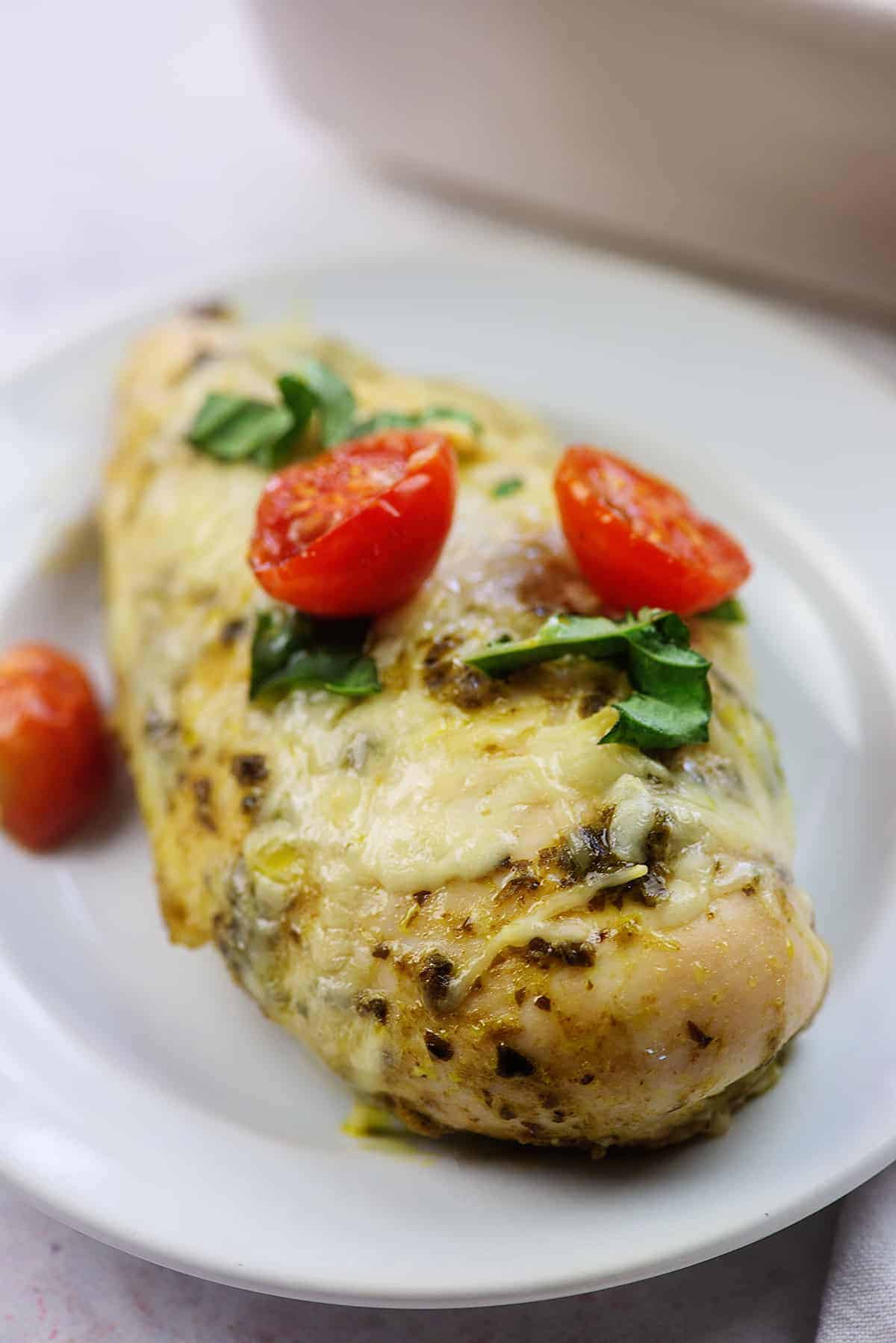 chicken pesto bake on white plate with cherry tomatoes