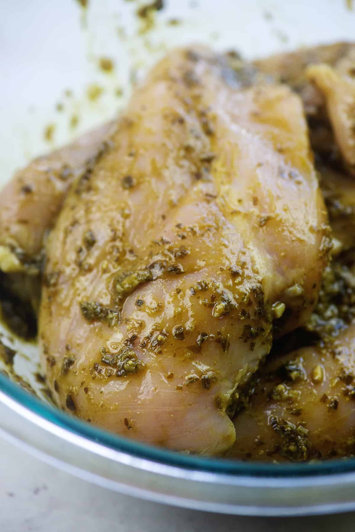 chicken breasts coated in pesto sauce in glass bowl