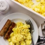 Overhead view of scrambled eggs and sausage links on a white plate.