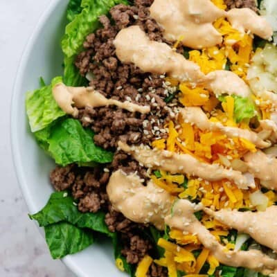 keto salad recipe with ground beef, cheese, pickles, and onions in white bowl