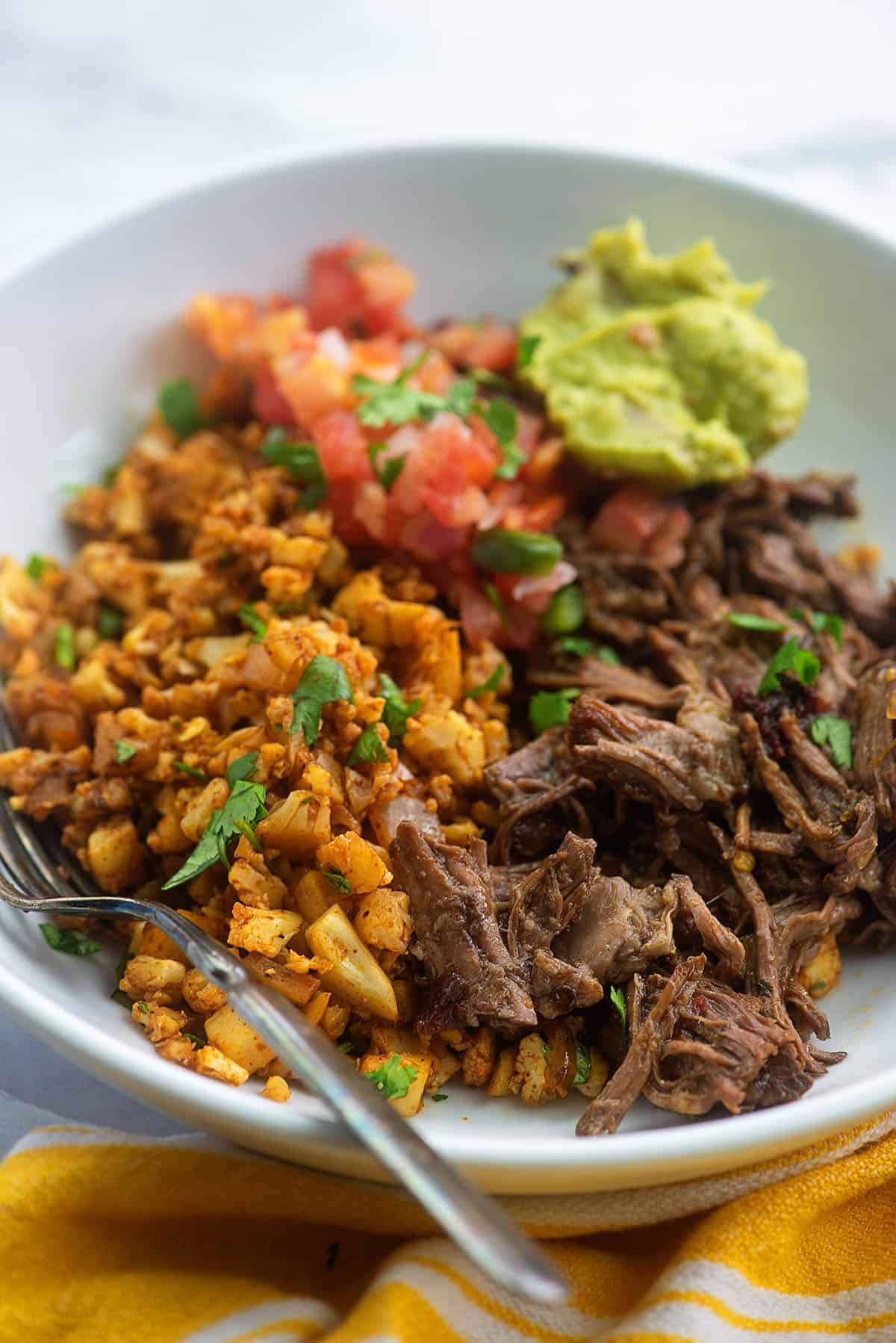 keto burrito bowl with mexican cauliflower rice and shredded beef in white bowl