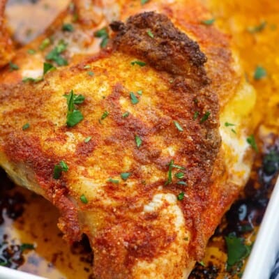 A close up of a roasted chicken breast in a white baking dish