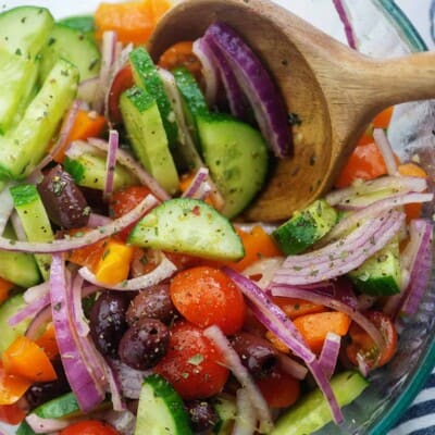 cucumbers, tomatoes, onions, and olives in glass mixing bowl