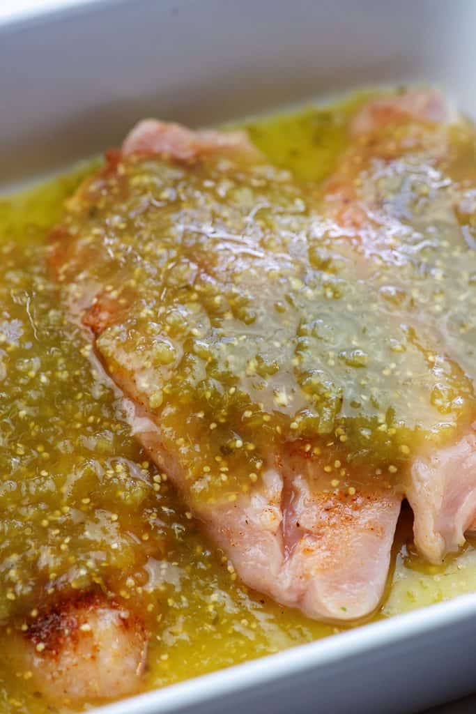 chicken breasts in white baking dish with salsa verde over the top