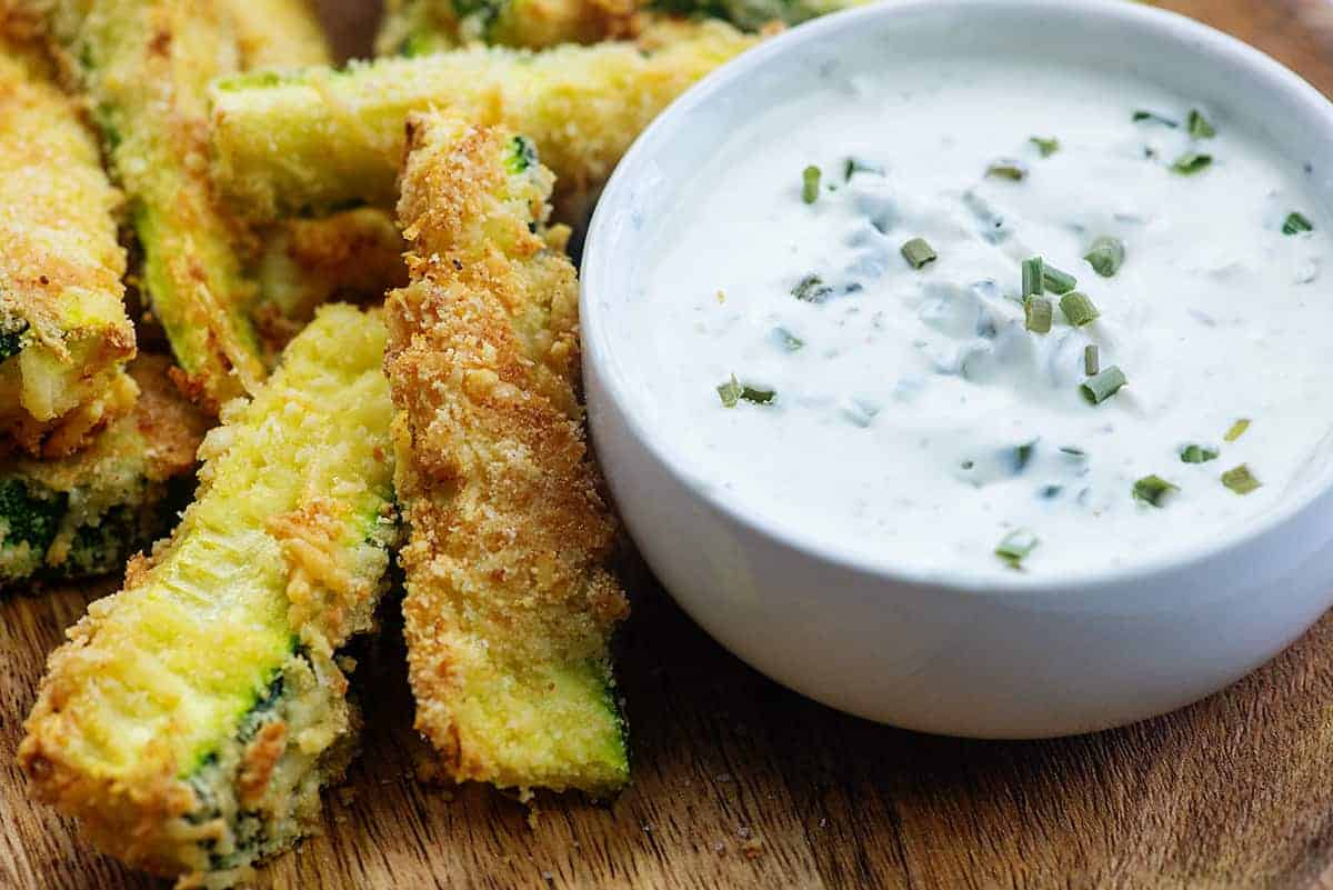 zucchini fries on cutting board with bowl of ranch dressing