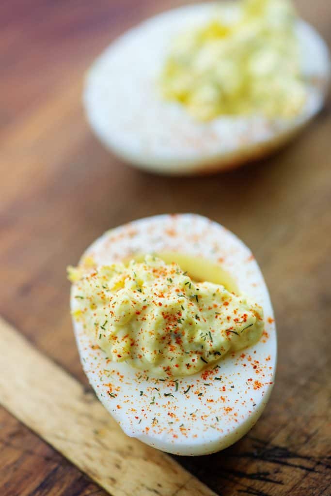 deviled eggs with paprika on wooden cutting board