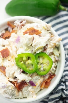 chicken salad in white bowl with jalapeno slices on top