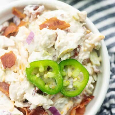 chicken salad in white bowl with jalapeno slices on top