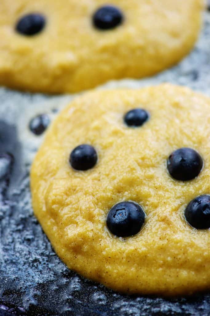 coconut flour pancakes on griddle with blueberries