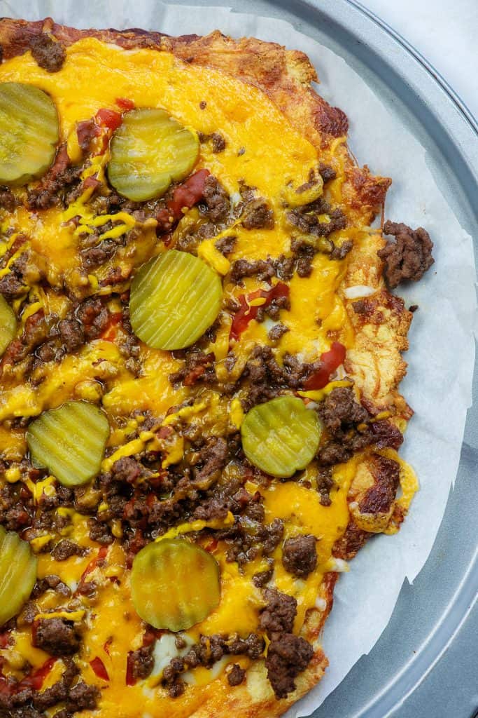 keto cheeseburger pizza recipe on parchment lined baking sheet