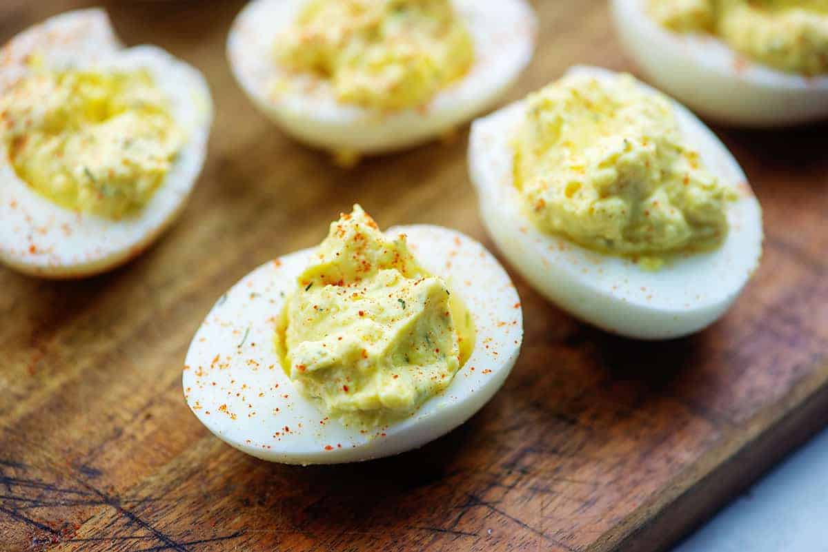 deviled eggs with paprika garnish on wooden cutting board