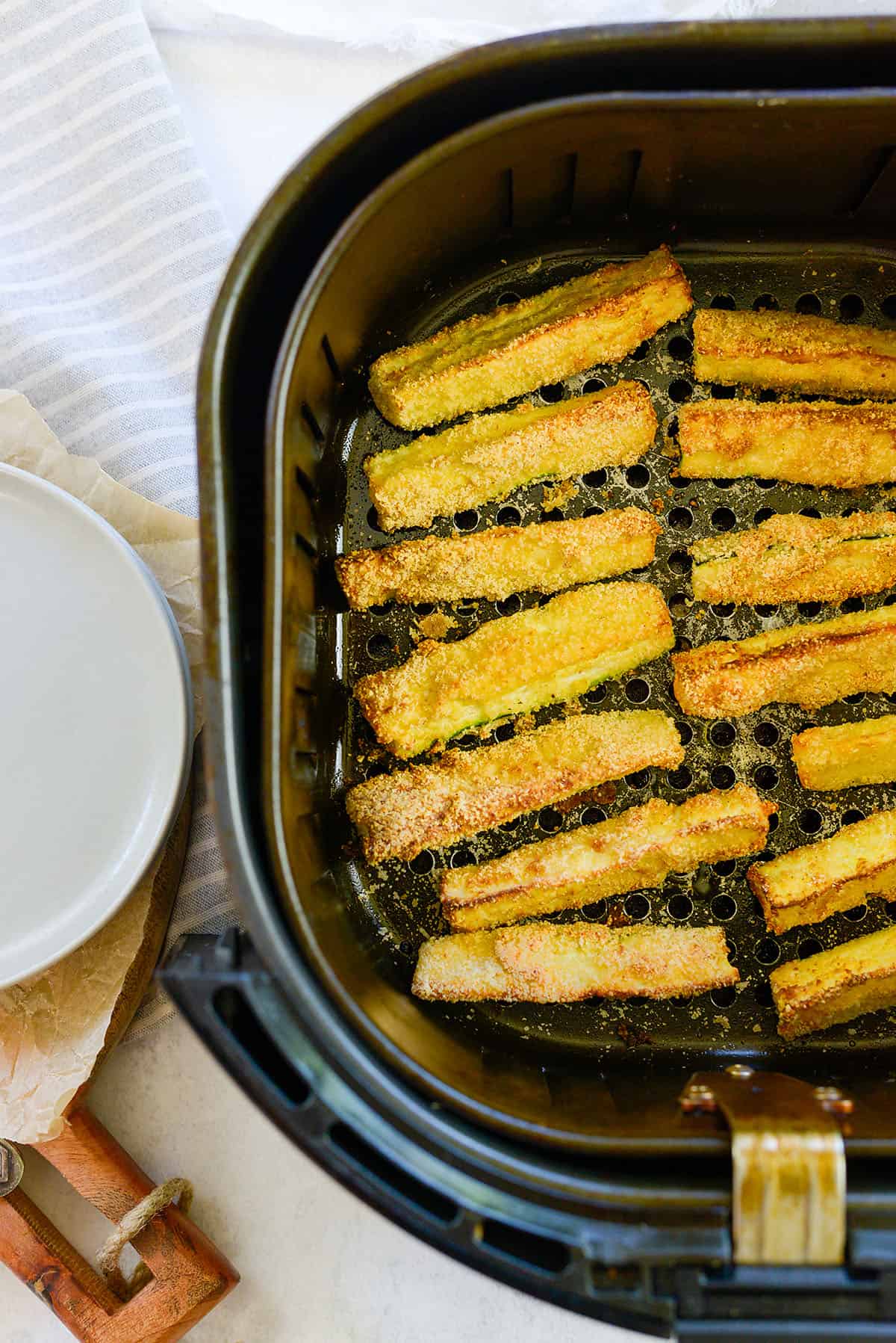 zucchini fries in air fryer basket.