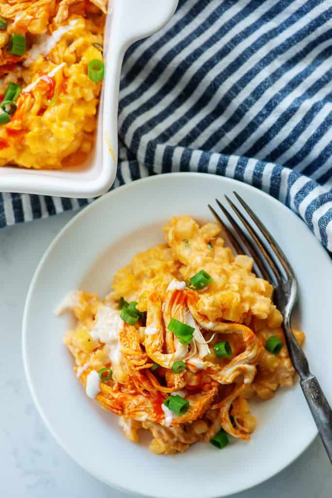 buffalo chicken and cauliflower casserole on white plate next to a blue striped napkin