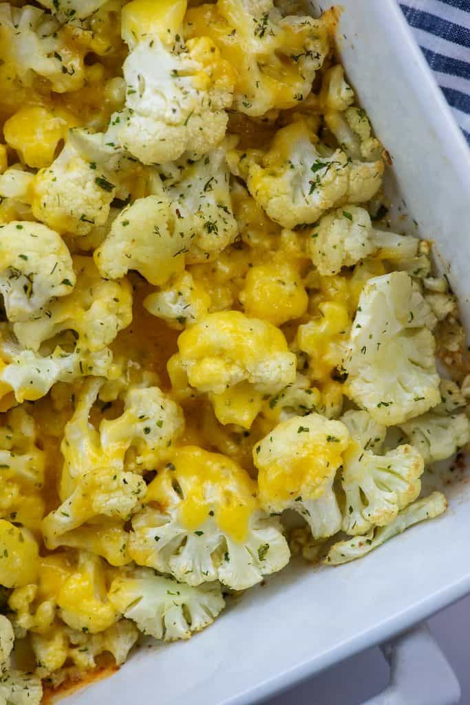 cauliflower covered in cheese in white baking dish