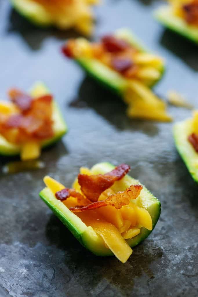 zucchini slices with cheddar and bacon on baking sheet