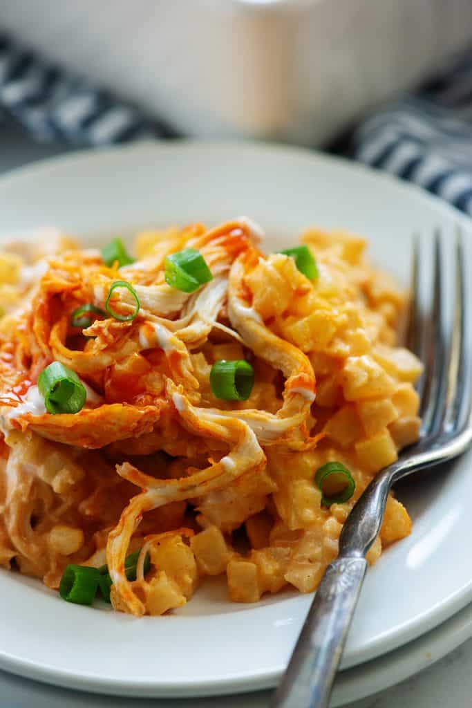 close up of buffalo chicken casserole on white plate with vintage fork