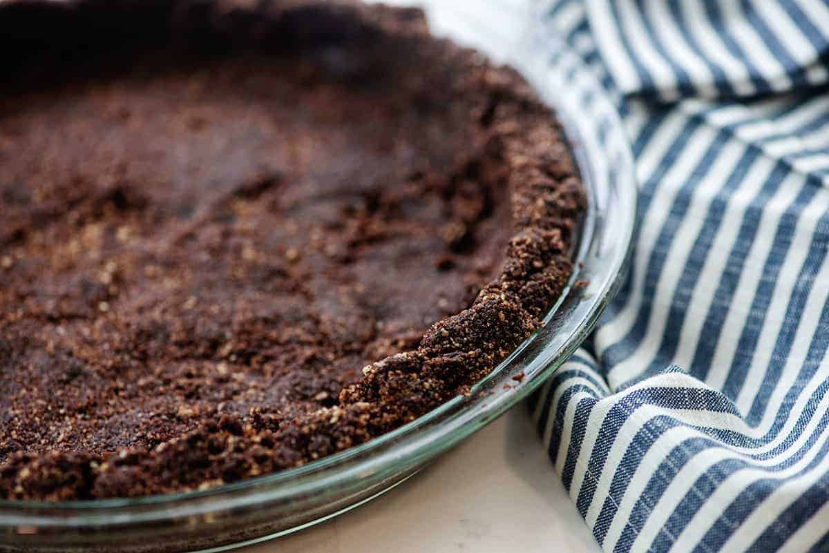 keto chocolate pie crust in pie plate with blue striped napkin