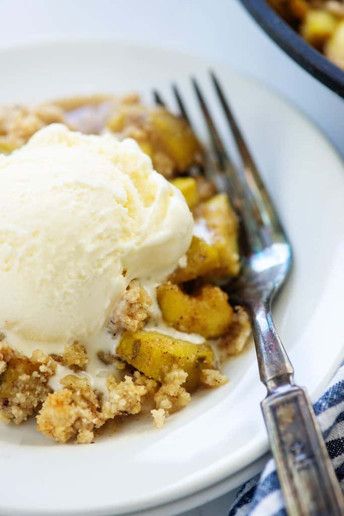 zucchini cobbler on white plate with ice cream on top