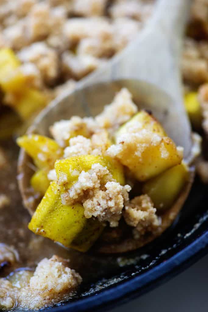 keto apple crisp on wooden spoon in cast iron skillet