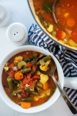 veggie soup in white bowl with salt and pepper shaker