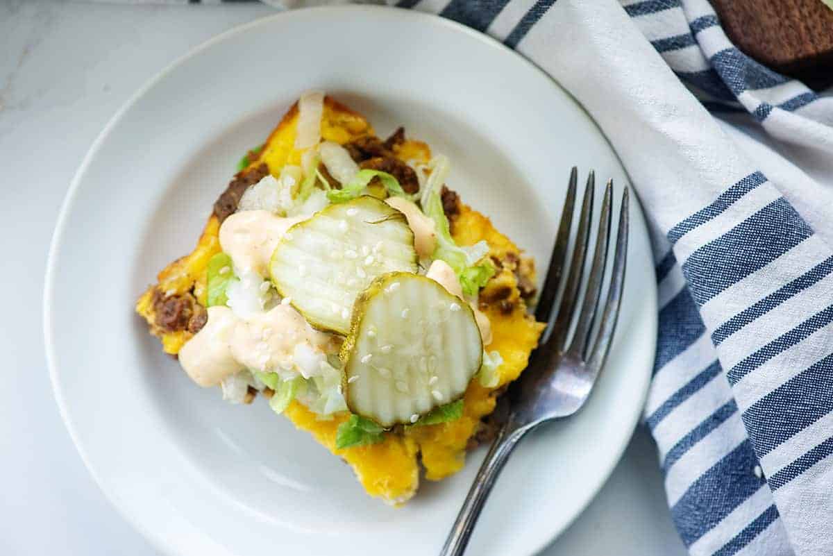 pickles, lettuce, and special sauce on top of cheeseburger casserole on white plate