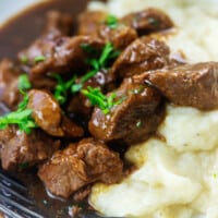 low carb beef tips on white plate with mashed cauliflower