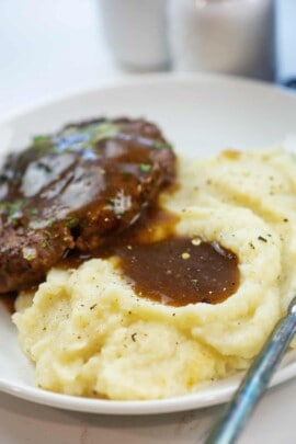 mashed cauliflower and hamburger steak topped with gravy on white plate