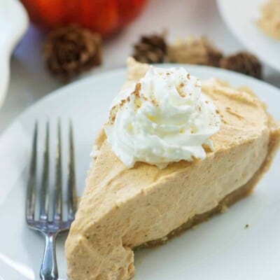 no bake pumpkin pie slice on white plate with whipped cream on top