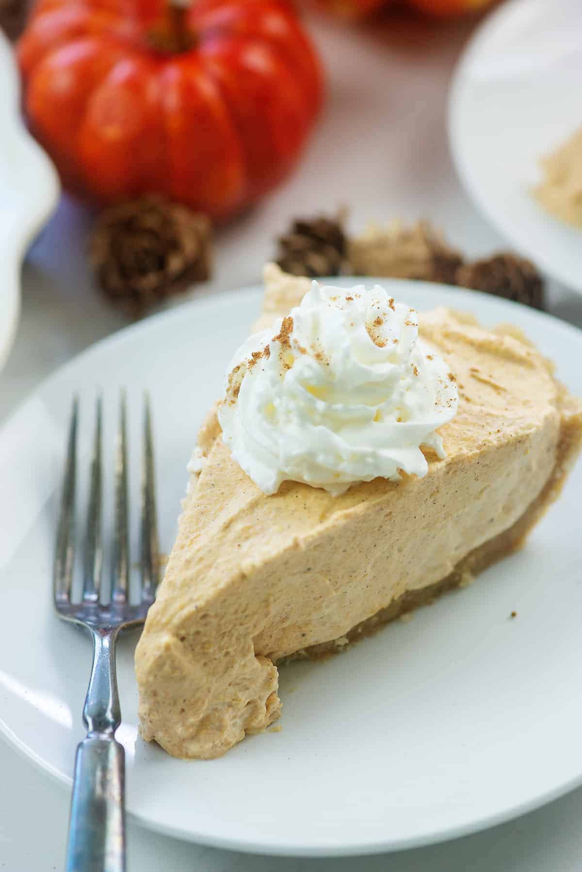 no bake pumpkin pie slice on white plate with whipped cream on top