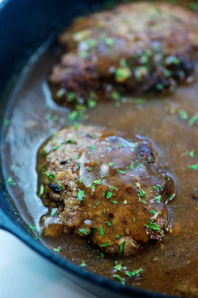 salisbury steaks in cast iron skillet topped with gravy