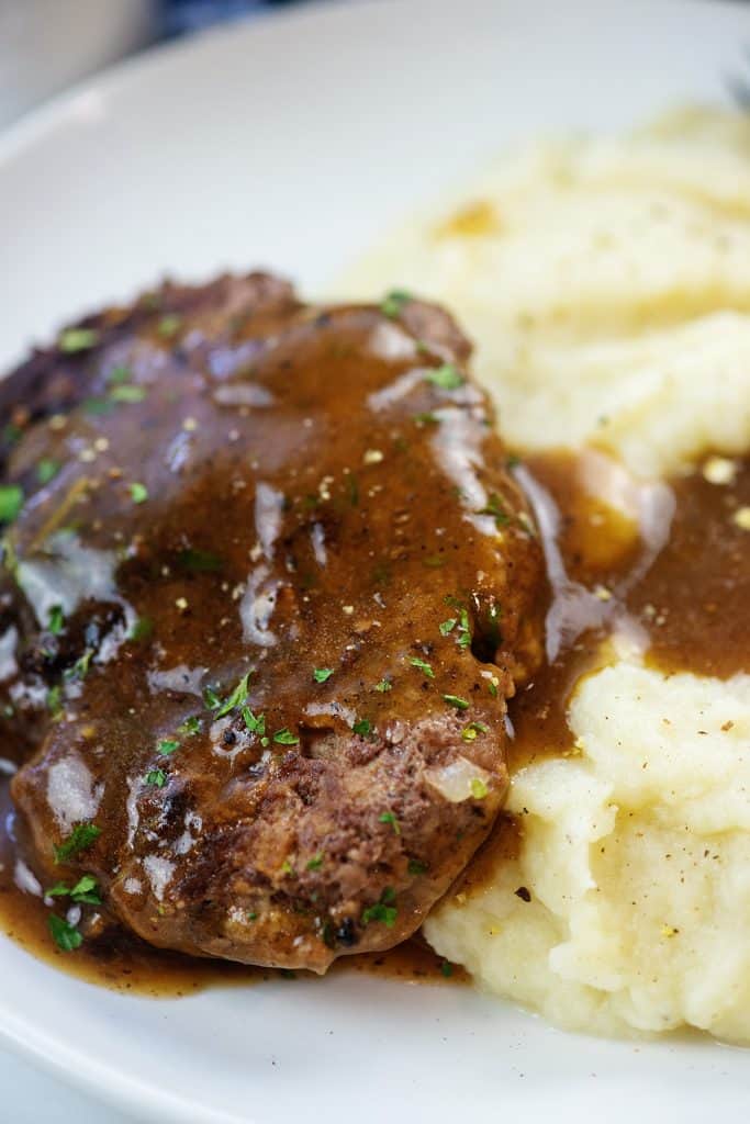 salisbury steak with gravy and mashed cauliflower on white plate