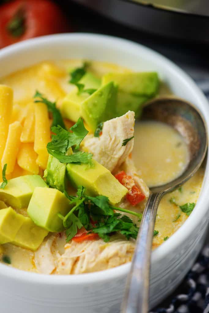 chicken fajita soup topped with avocado in white bowl with vintage spoon