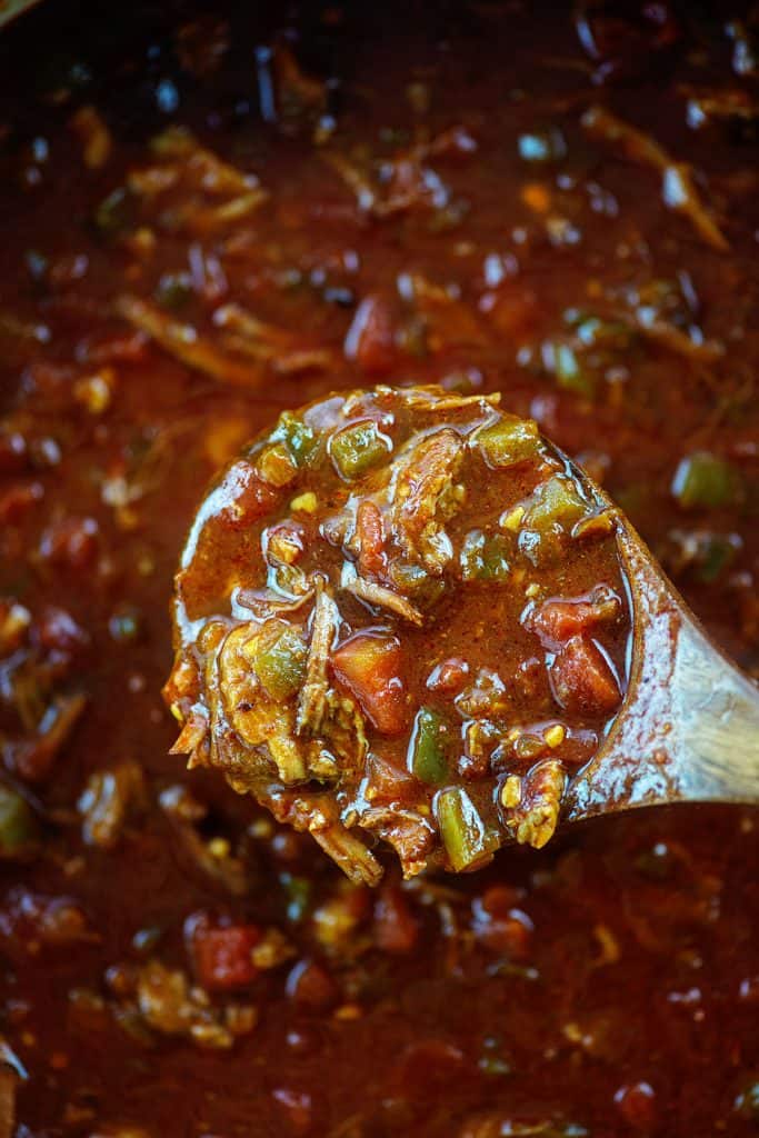 thick chili in wooden ladle.