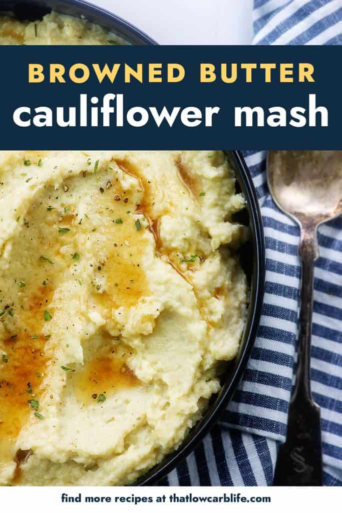 Cauliflower mash in black bowl with butter on top.