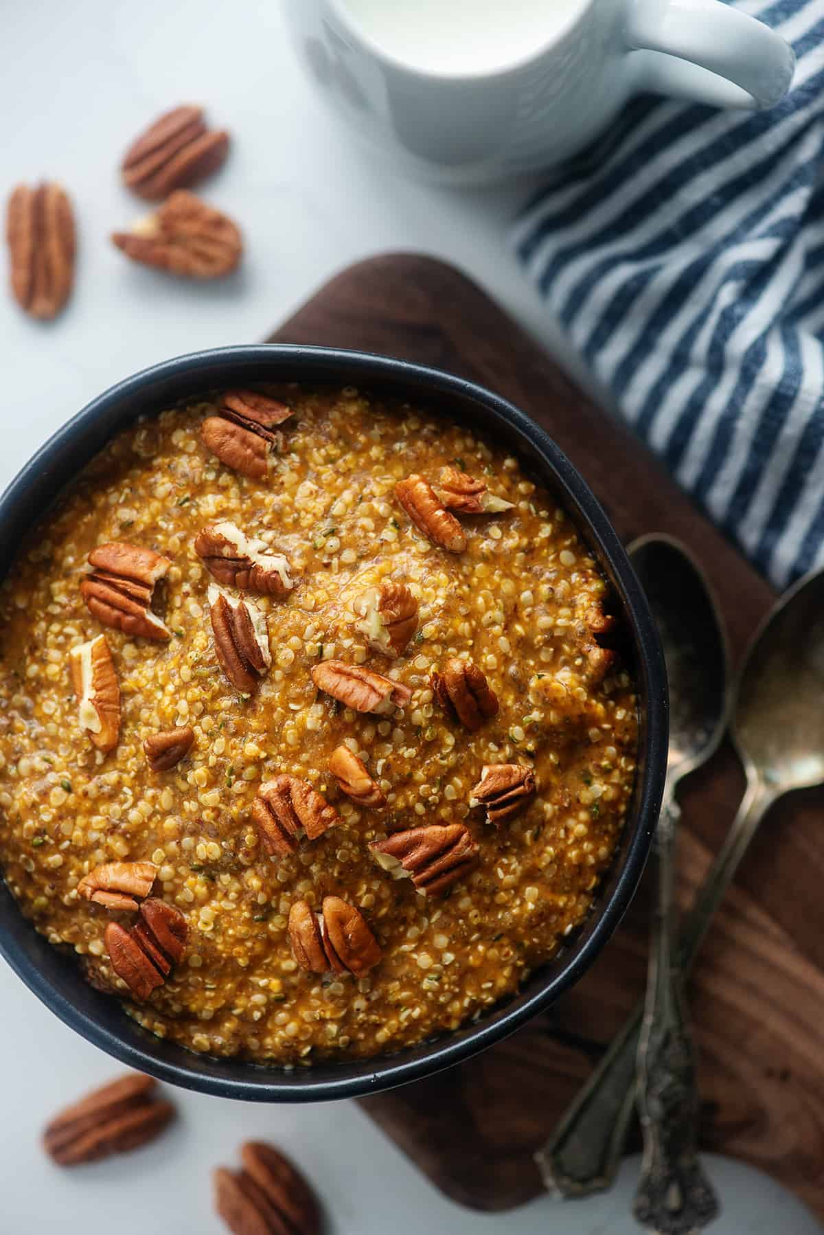 pumpkin noatmeal in black bowl topped with pecans