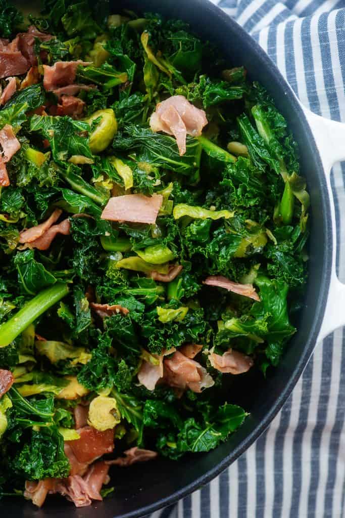 white skillet full of sauteed kale and brussels sprouts.